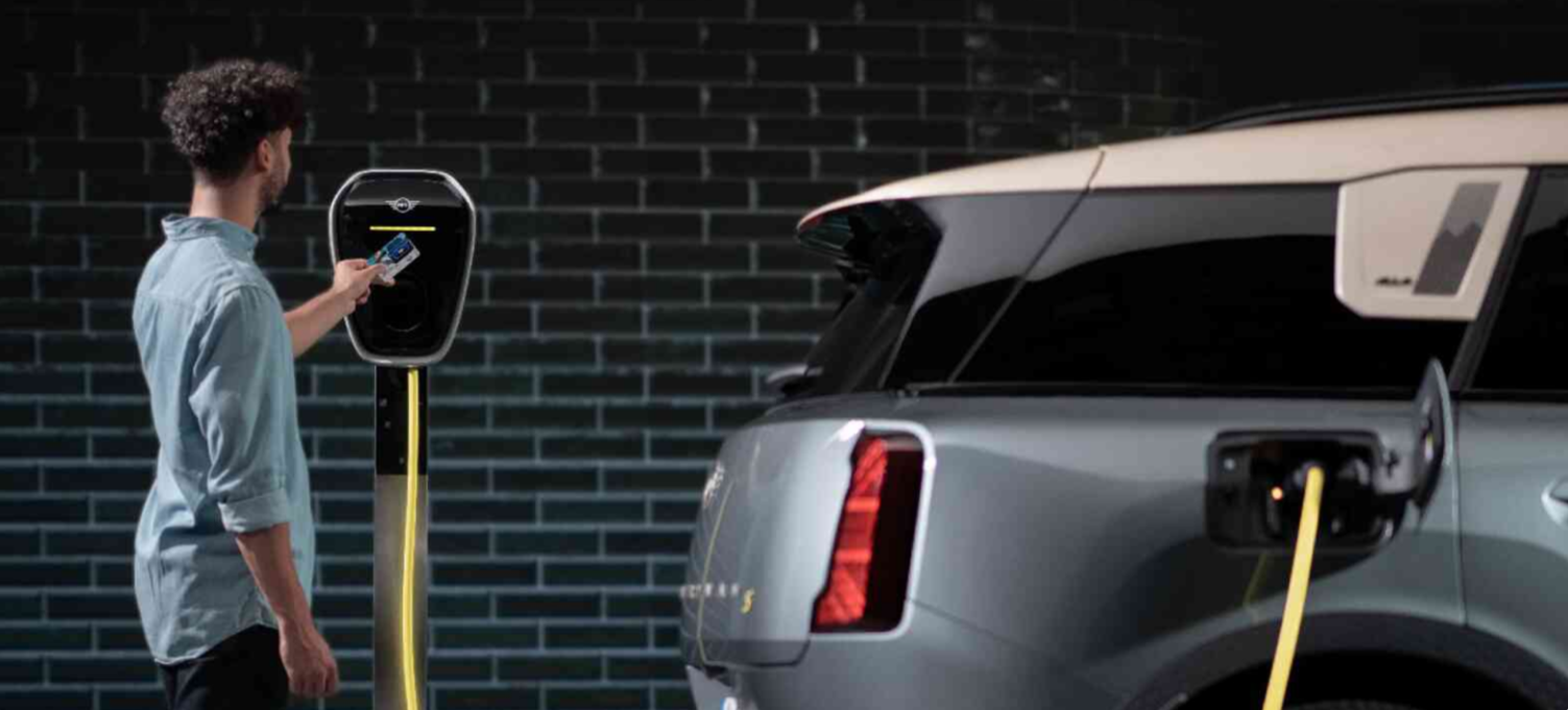 A man charges his MINI Countryman SE ALL4 using a MINI Wallbox .