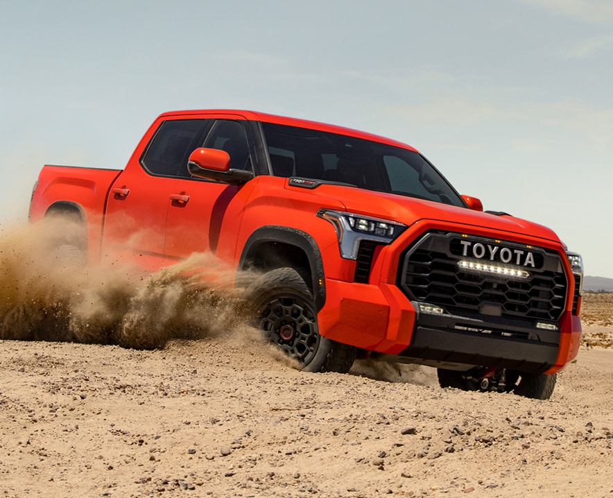 The New 2023 Toyota Tundra at Mechanicsville Toyota in Mechanicsville, VA | Orange Toyota Tundra driving on dirt with dirt flying into the air