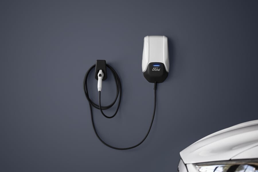 An installer mounting a Ford Charge Station Pro to a wall with a Ford F-150 Lightning® in the garage