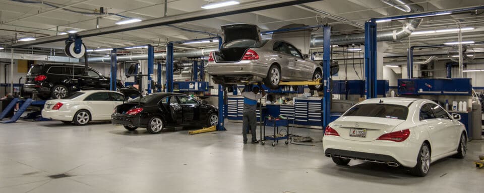 Inside a Mercedes-Benz service center with a service technician maintaining a vehicle