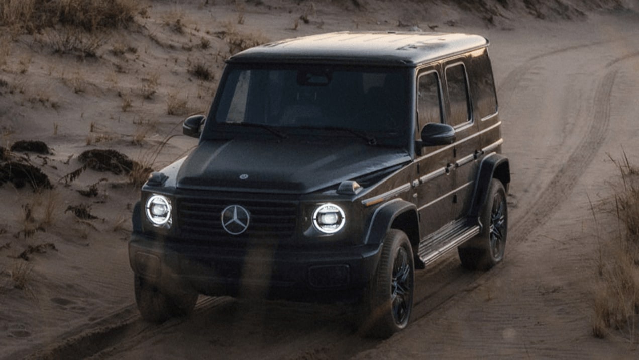 Exterior shot of a Mercedes-Benz G-Class SUV driving along a beach road