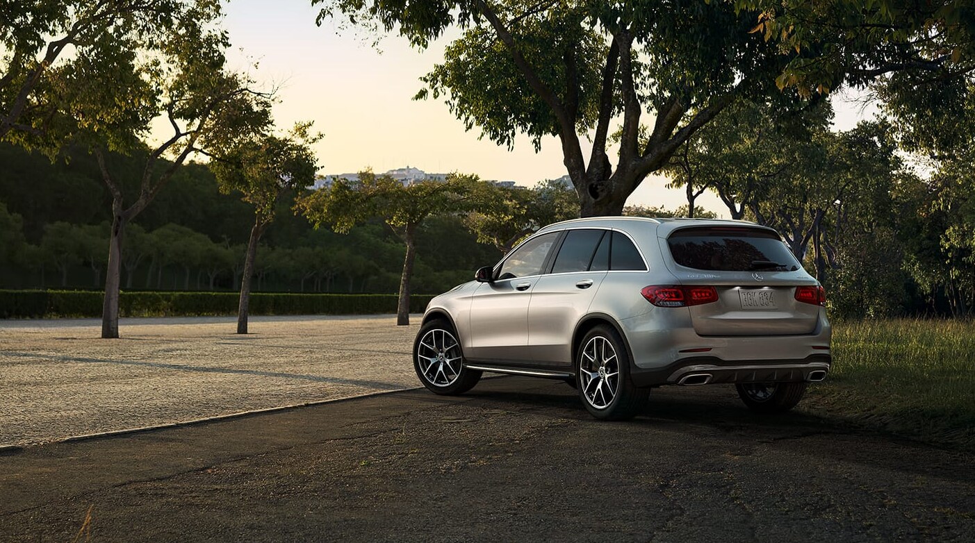 A view of a silver 2022 Mercedes-Benz GLC as it sits parked  by a tree with a view of the profile and back