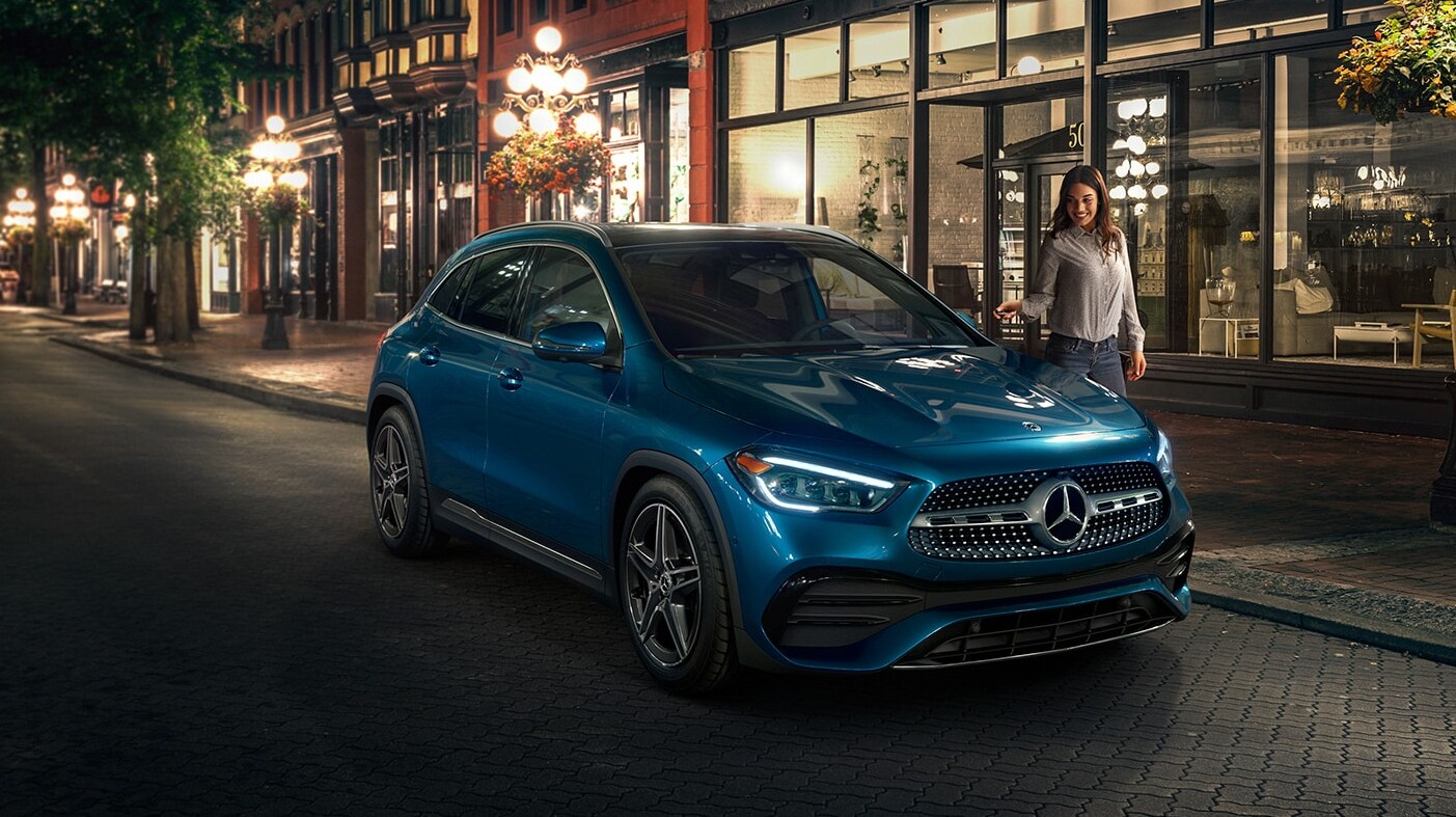 A profile view of a blue 2023 Mercedes-Benz AMG GLA 250 SUV parked at night on a city street