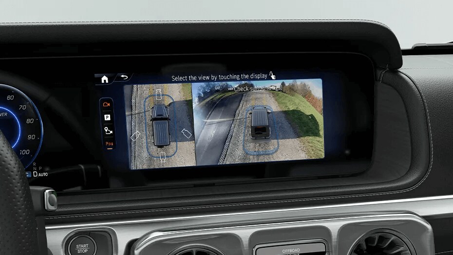 Learn about the safety features of the Mercedes-Benz G-Class Closeup shot of the front left headlamp on the Mercedes-Benz G-Class SUV and outside surroundings