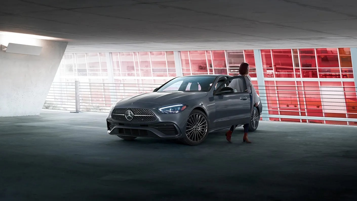 woman standing in a parking garage with a C-Class, red background