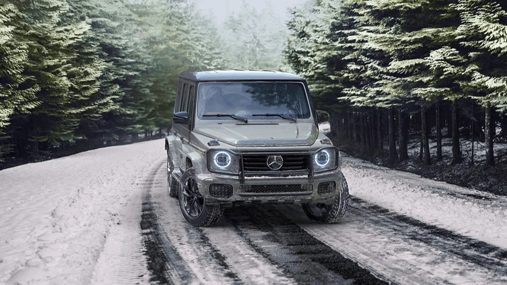 Rendered image of a Mercedes-Benz G-Class SUV driving through a snow-covered forest road