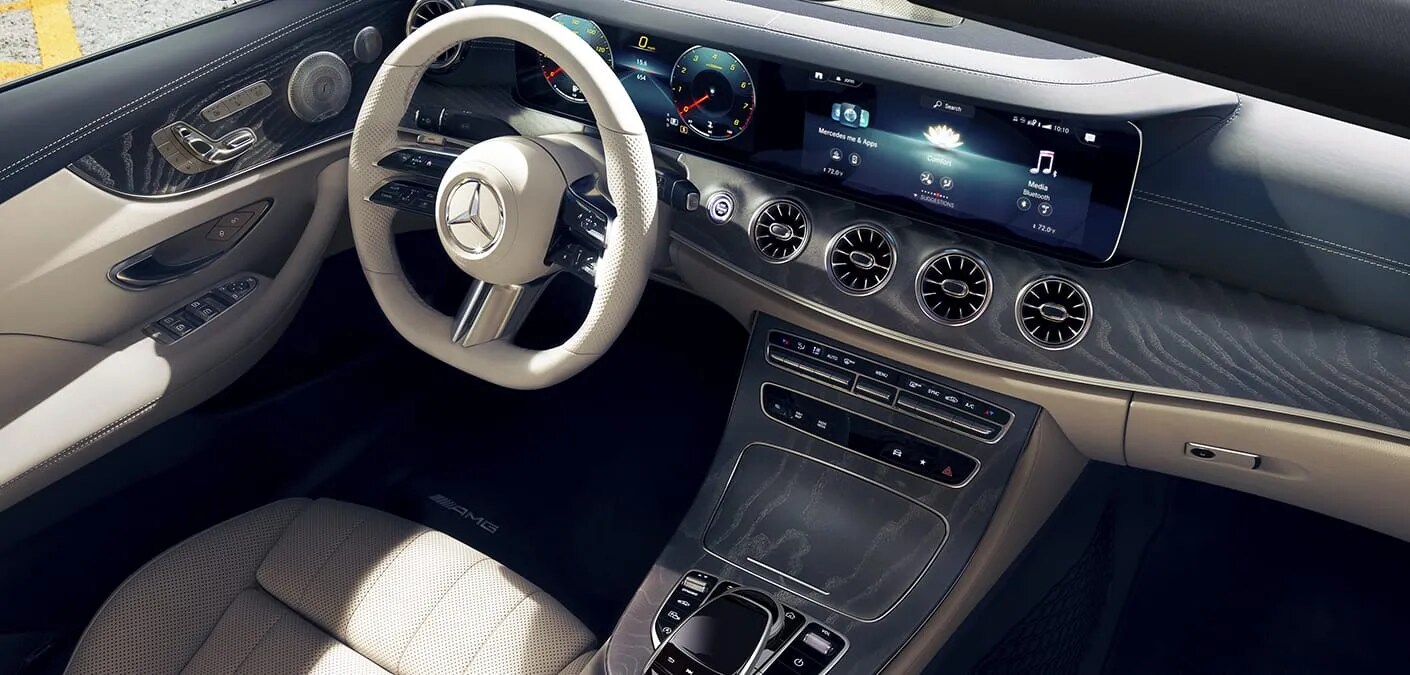 Inside of a Mercedes-Benz looking over the front driver seat and at the elegant dash Image of the inside of a luxury Mercedes-Benz vehicle, highlighting the front dash and steering wheel interior features
