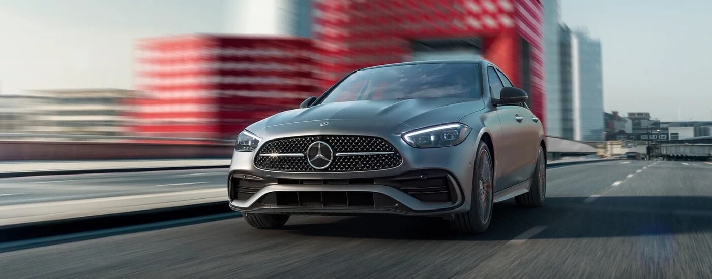 A grey 2024 Mercedes-Benz C-Class is shown on a city street after leaving a Mercedes-Benz dealer near Reading.