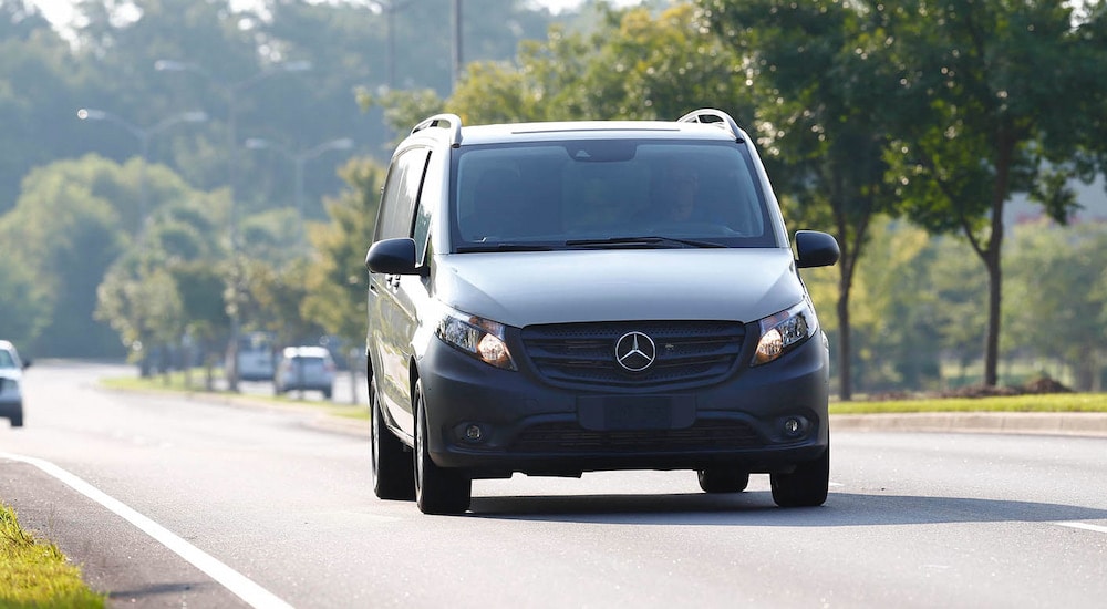 Head-on view of a 2024 Mercedes-Benz Metris driving on a tree-lined road.
