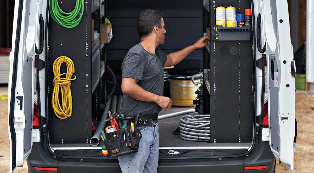 The rear of a white 2024 Mercedes-Benz Sprinter is shown with the doors open.