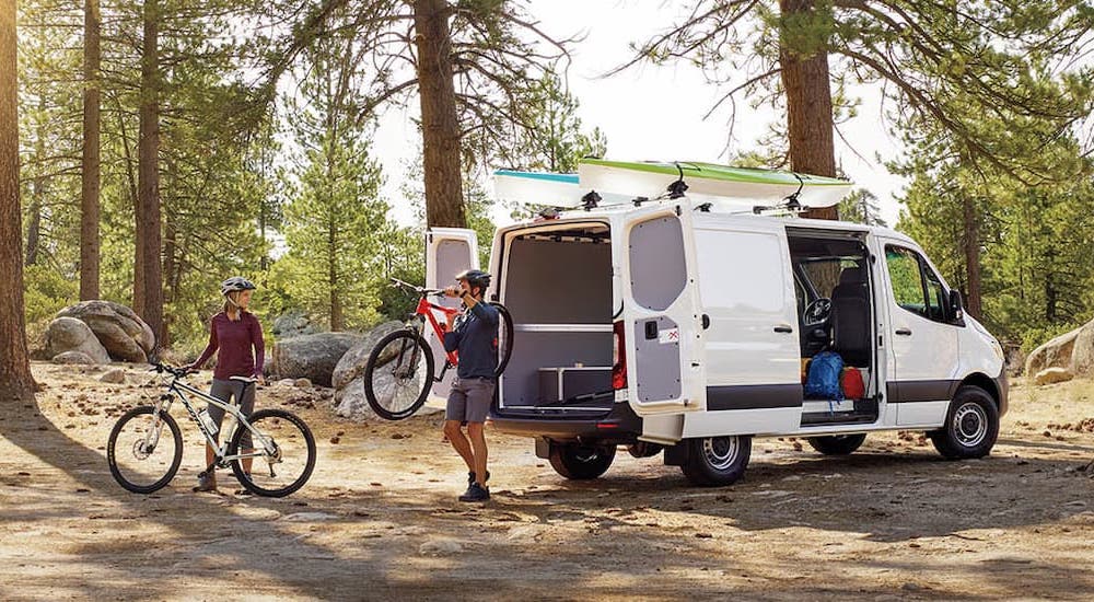 Two people unloading bicycles from the back of a white 2025 Mercedes-Benz Sprinter 2500 Cargo Van.