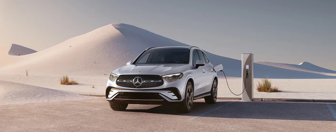 A white 2025 Mercedes-Benz GLC parked in a desert and charging.