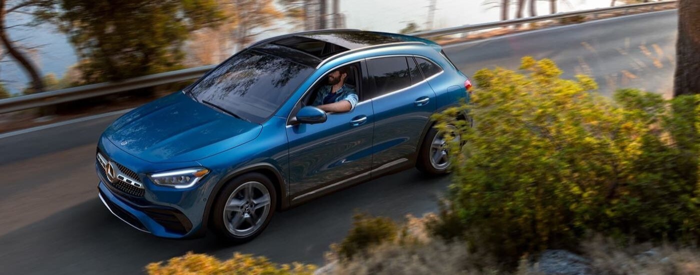 Overhead view of a blue 2023 Mercedes-Benz GLA 250 driving by a lake.