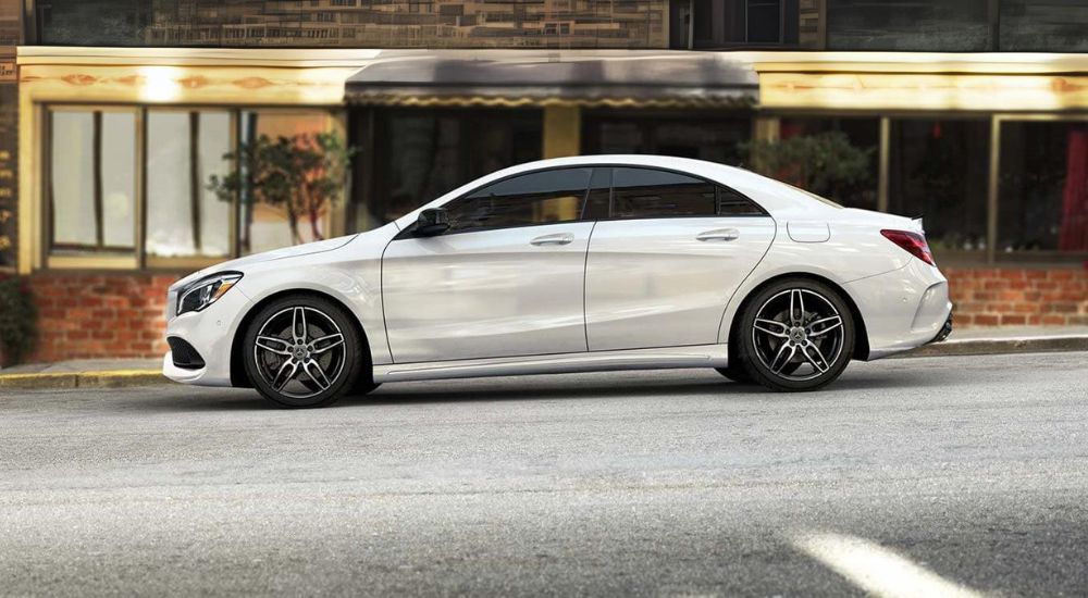 A popular used Mercedes-Benz for sale near West Chester, a white 2019 Mercedes-Benz CLA, is shown from the side parked on a city street.