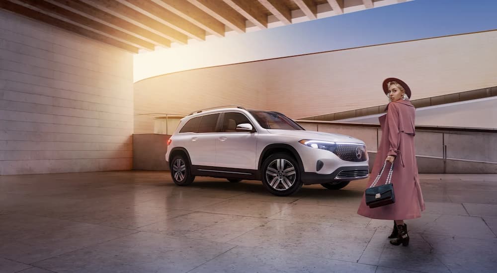 A woman is walking towards a white 2024 Mercedes-Benz EQB 300.