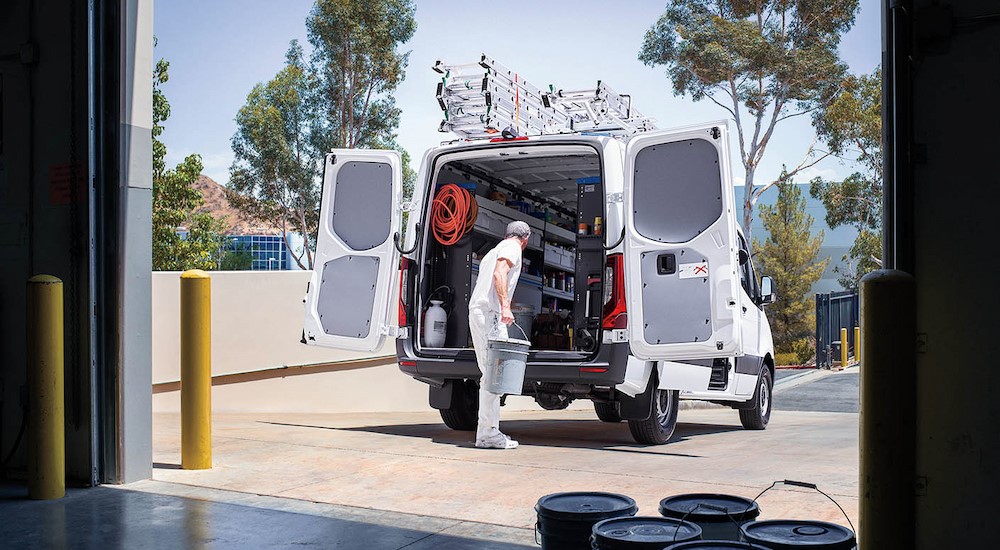 A person is shown unloading buckets from the cargo area in a 2024 Mercedes-Benz Sprinter 2500 for sale near West Chester.