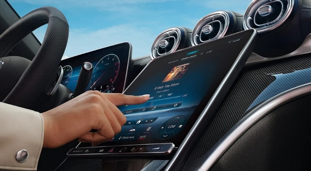 A person is shown using the touch-screen in a 2025 Mercedes-Benz C 300.
