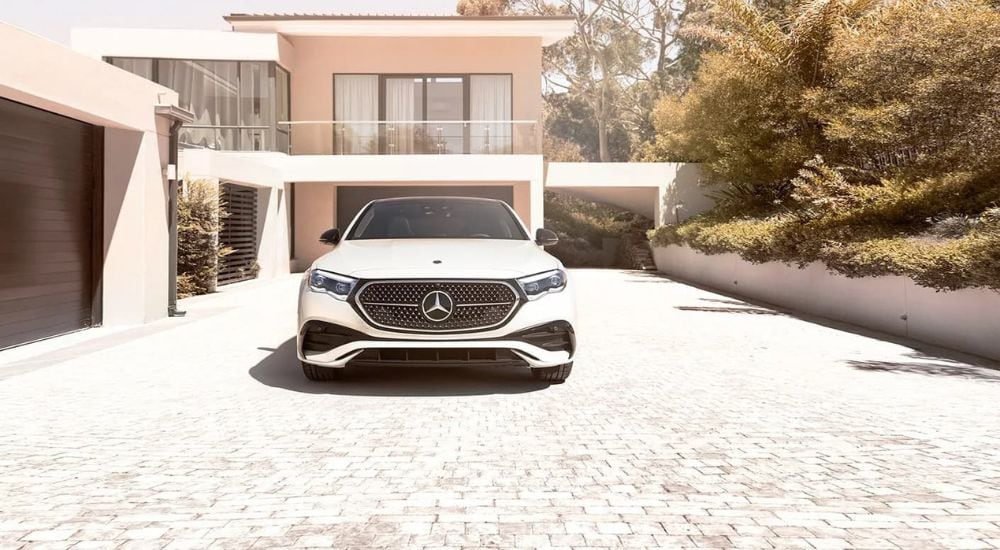A white 2024 Mercedes-Benz E-Class is shown parked on the driveway of a modern home.