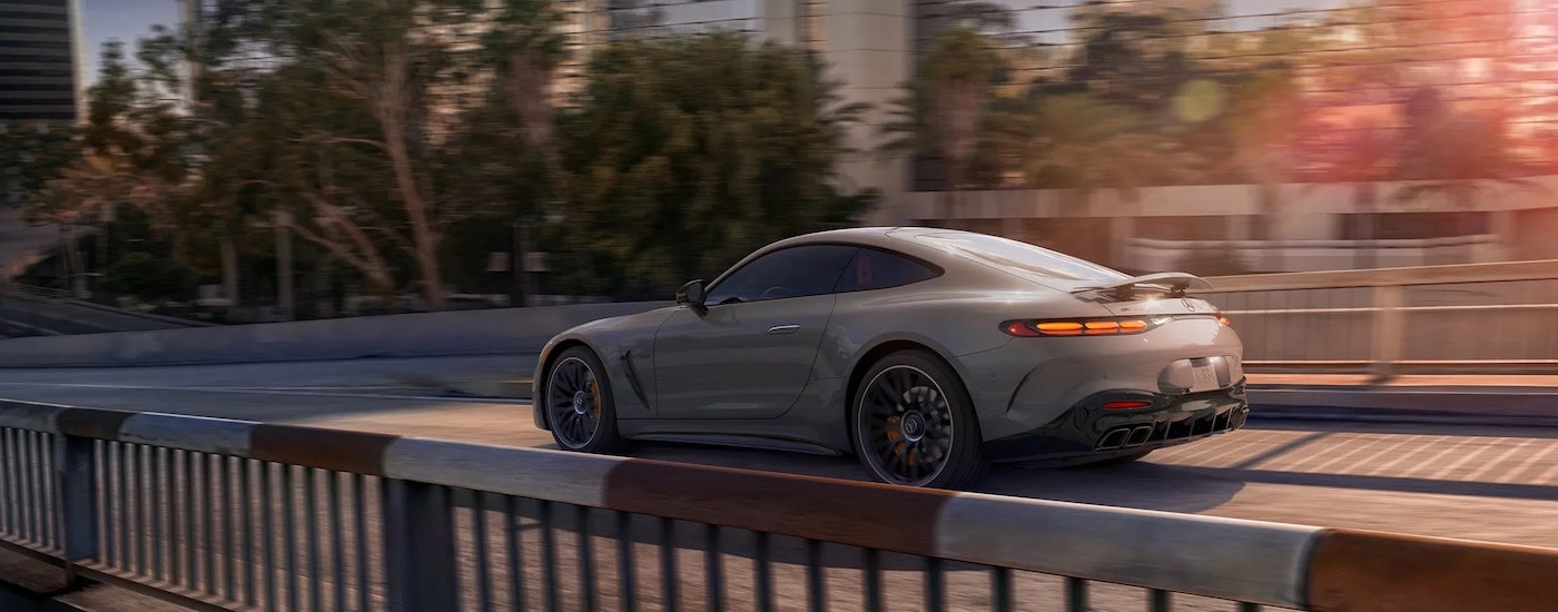A tan 2024 Mercedes-Benz AMG GT Coupe is shown from the rear at an angle after leaving a Mercedes-Benz dealer.