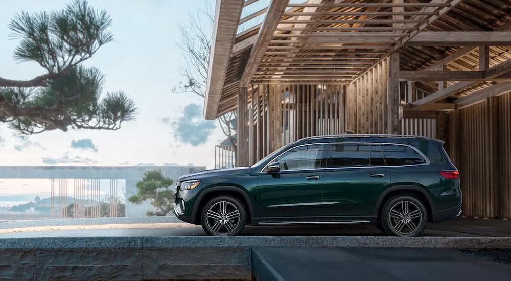 Side angle view of a green 2025 Mercedes-Benz GLS 450 parked outside a building.