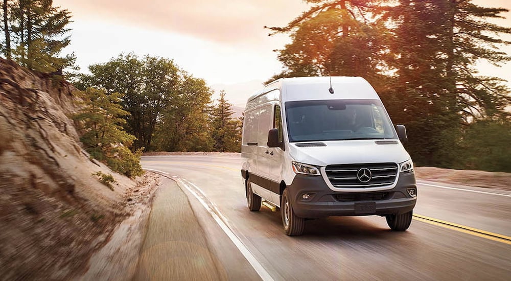 A white 2025 Mercedes-Benz Sprinter 2500 Cargo Van driving around a bend.