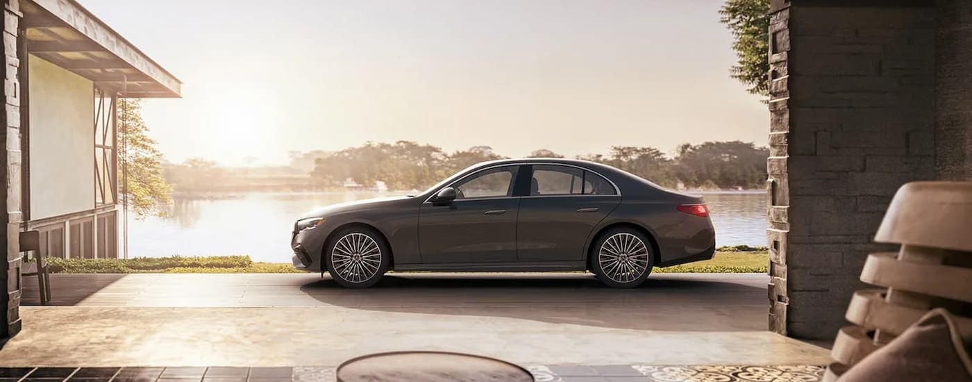 A side angle view of a grey 2024 Mercedes-Benz E 350 4MATIC parked on a driveway.