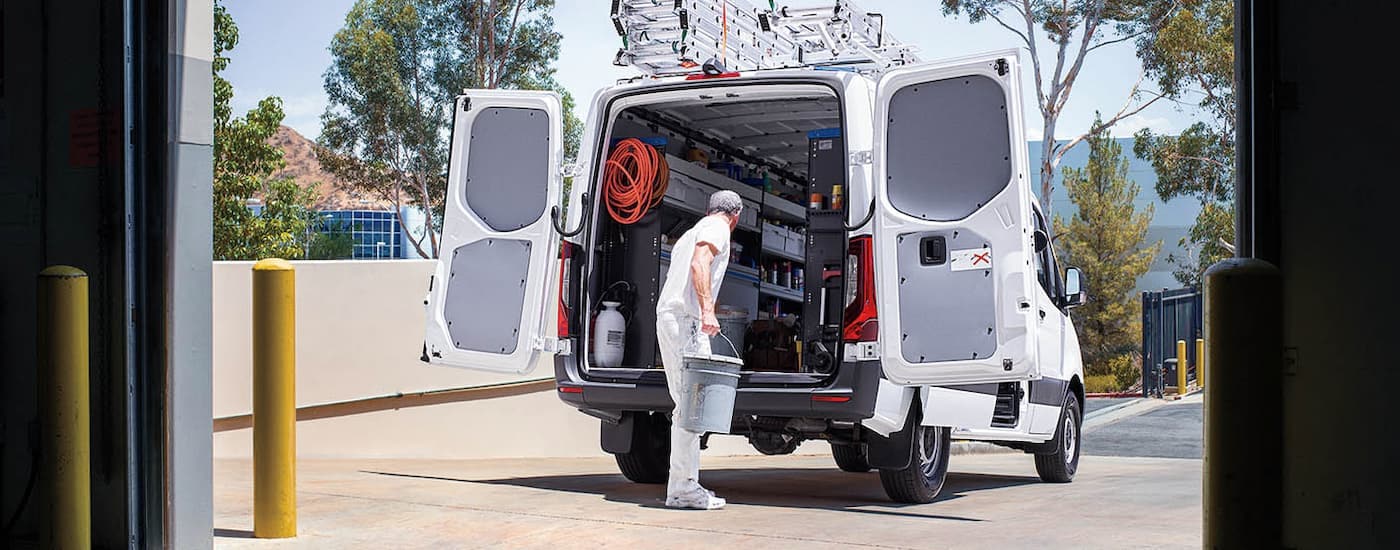 A painter is getting supplies from the rear of a white 2025 Mercedes-Benz Sprinter 4500.