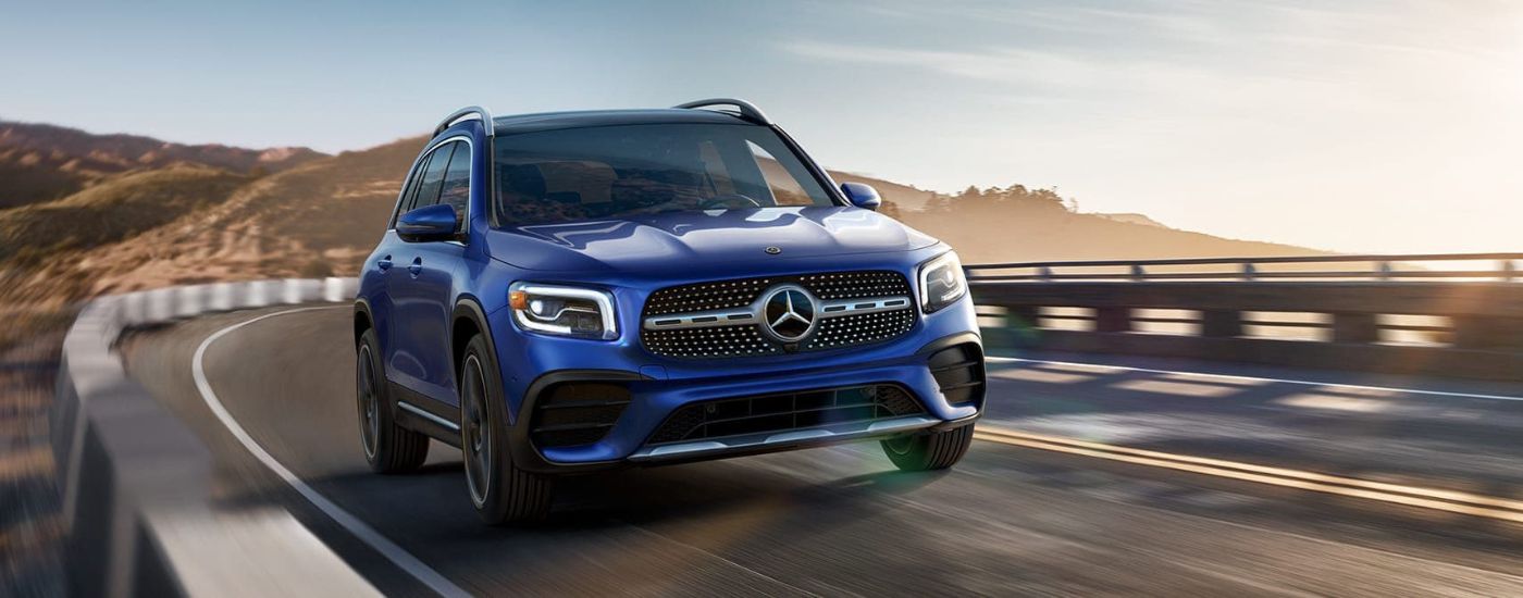 A popular used Mercedes-Benz for sale in Medford, a blue 2020 Mercedes-Benz GLB, is shown rounding a corner.