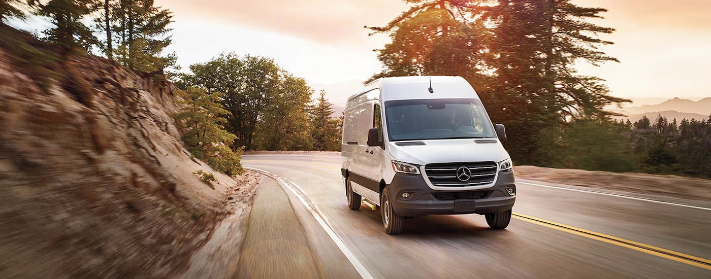 A white 2024 Mercedes-Benz Sprinter 2500 cargo van driving on a mountain highway.