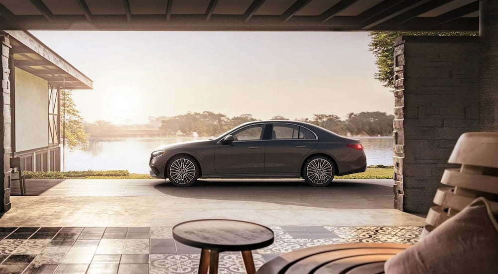 A side view of a grey 2024 Mercedes-Benz E 350 4MATIC parked by a house.