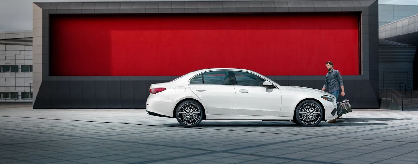 Side angle view of a person entering a parked white 2025 Mercedes-Benz C 300 4MATIC.