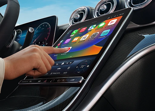 Hand tapping the C-Class centre touchscreen showing Apple CarPlay app icons