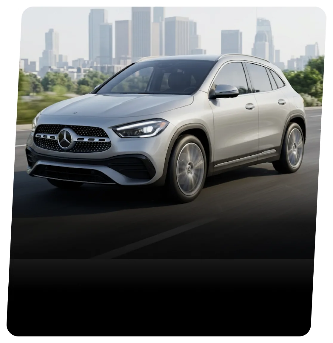 Silver Mercedes-Benz GLA SUV on a highway with a city skyline behind