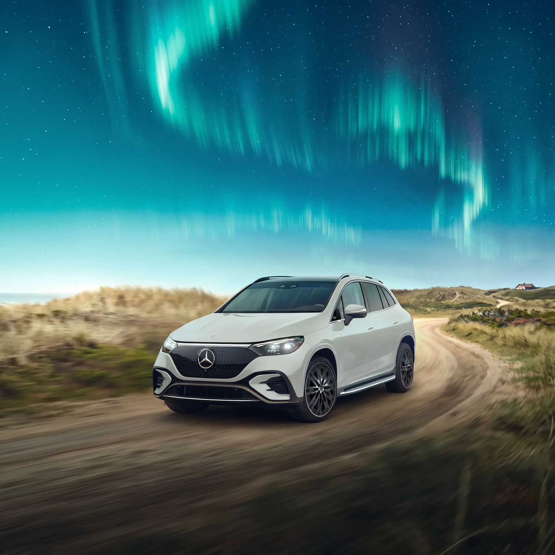 A white Mercedes-Benz EQE SUV driving a dirt road at dusk under an aurora, front three-quarter view