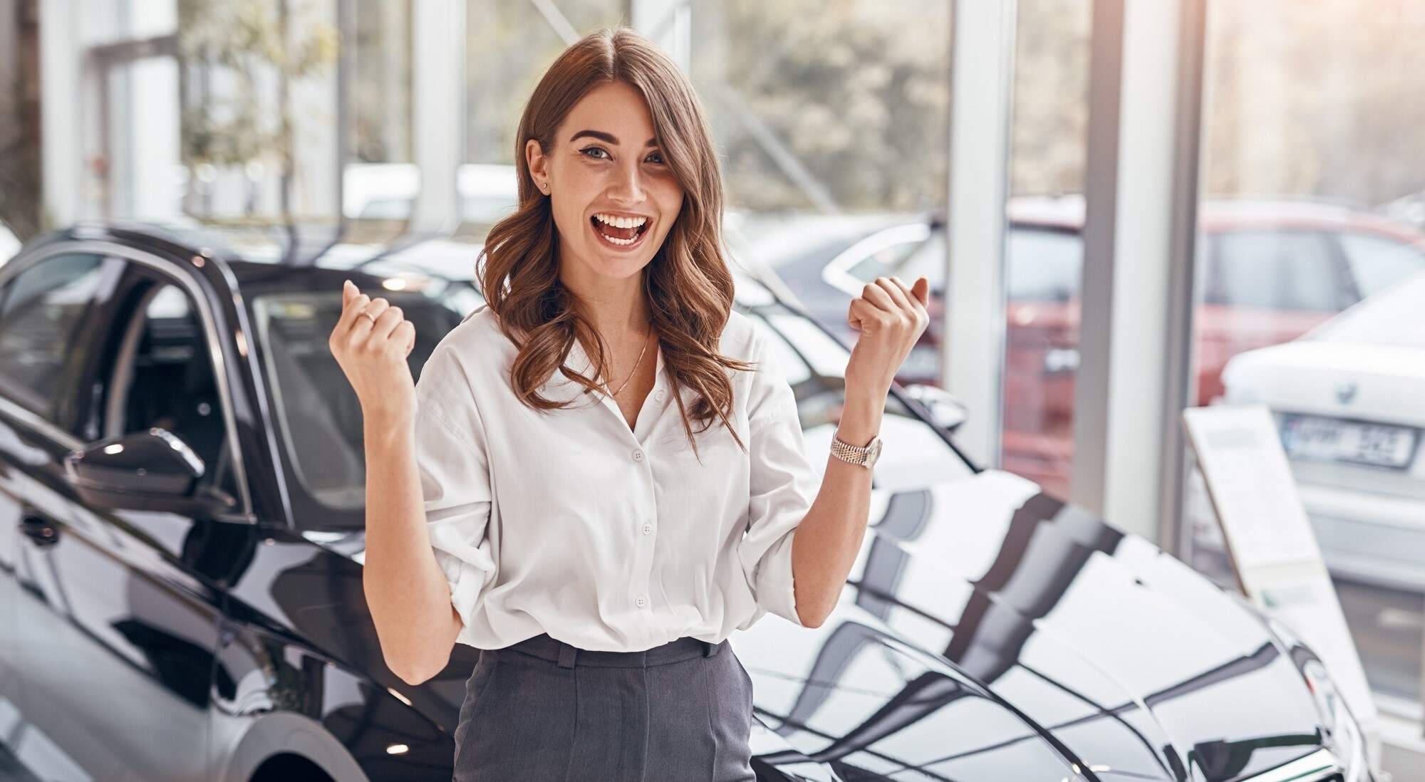 A customer smiling beside a car in a dealership showroom