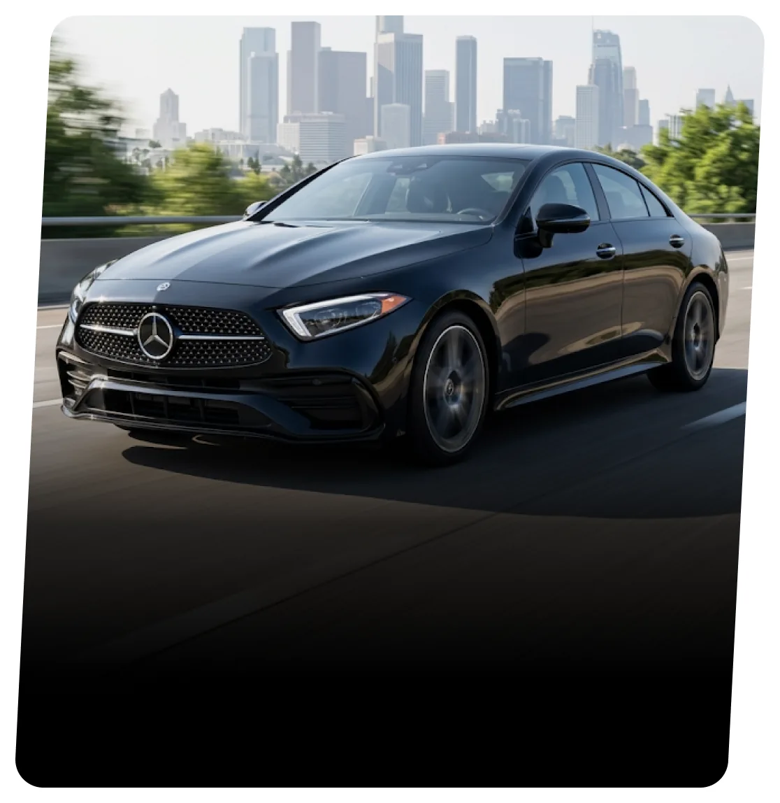 Black Mercedes-Benz coupe on a highway with a city skyline behind