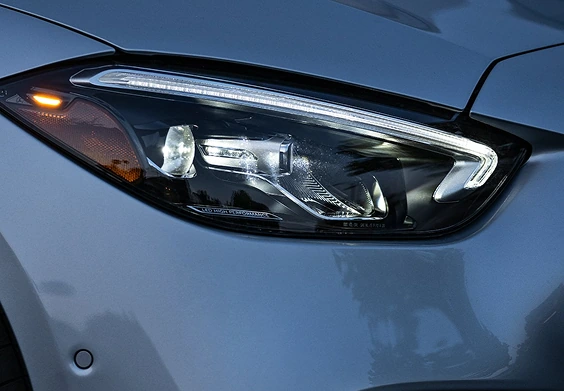 Close-up of a C-Class Sedan LED headlamp with its amber turn signal lit on a blue-grey body