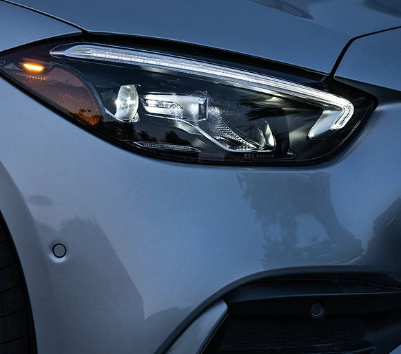 Close-up of a C-Class LED headlamp on a blue-grey body