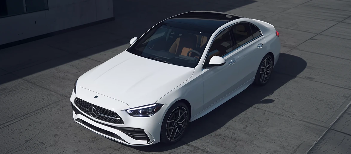 High angle of a white C-Class Sedan with a panoramic roof parked on a concrete lot