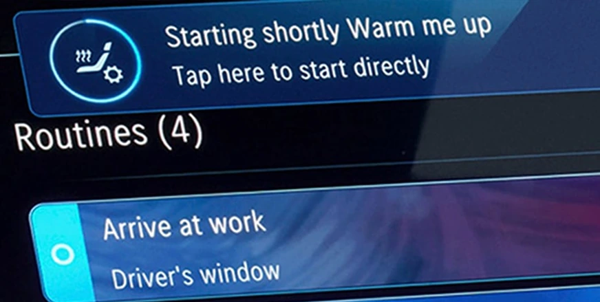 MBUX Routines screen with a "Starting shortly Warm me up" prompt above "Arrive at work" and "Driver's window" routines