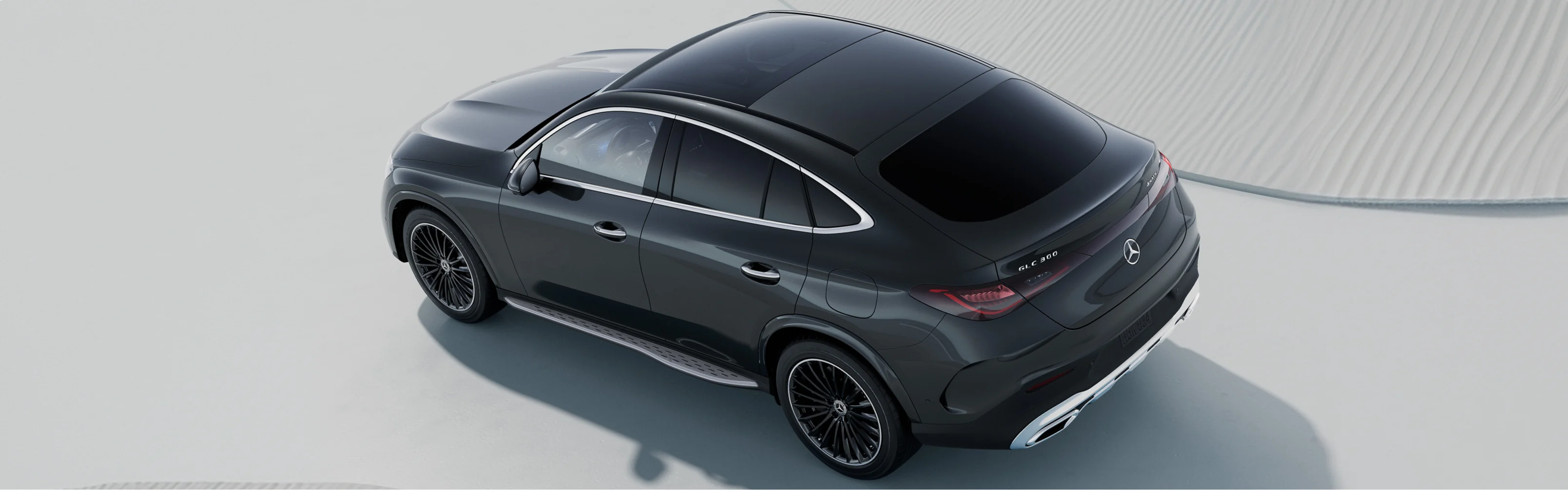 Overhead view of a dark grey 2027 Mercedes-Benz GLC Coupe on a pale sculpted surface