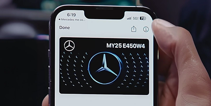 Hand holding an iPhone displaying a Mercedes-Benz Digital Vehicle Key card