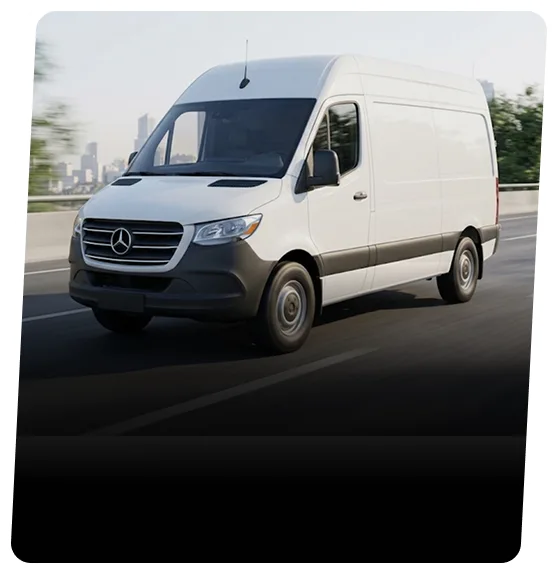 White Mercedes-Benz Sprinter van on a highway with a city skyline behind