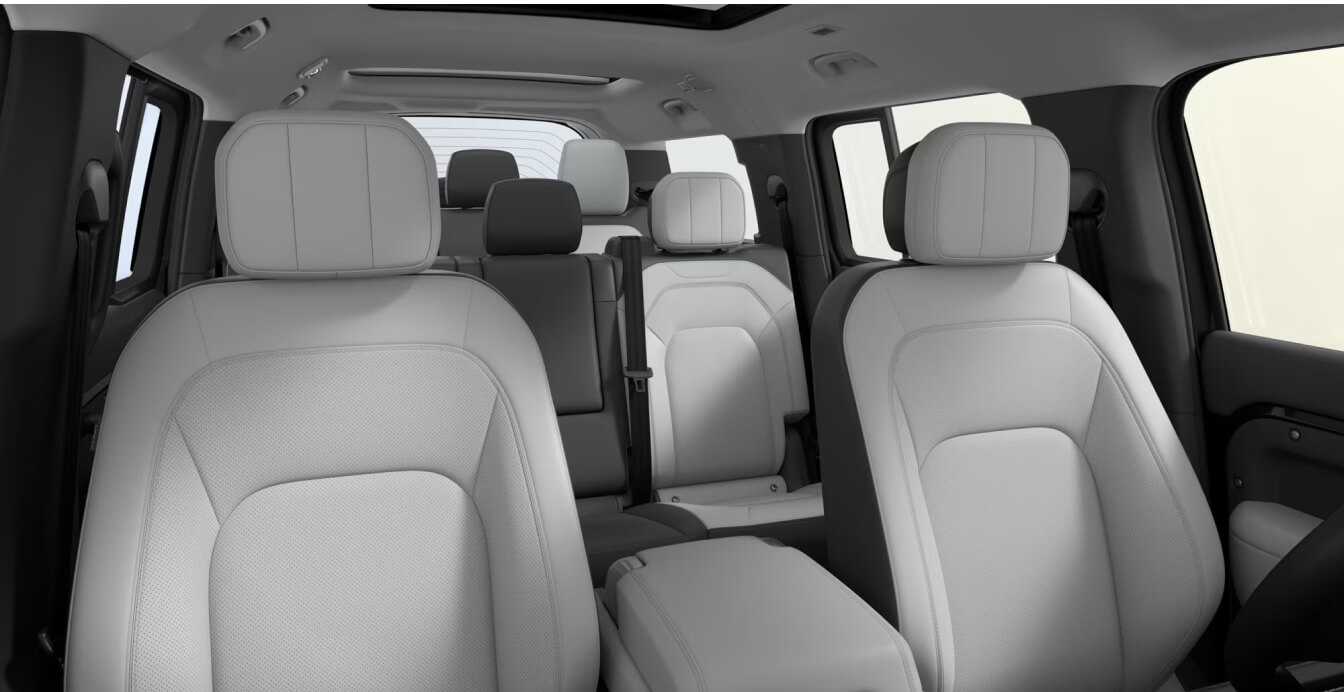 Interior view looking back from the front seats of a 2026 Land Rover Defender 130 cabin interior in Light Cloud/Lunar Ultrafabrics™.