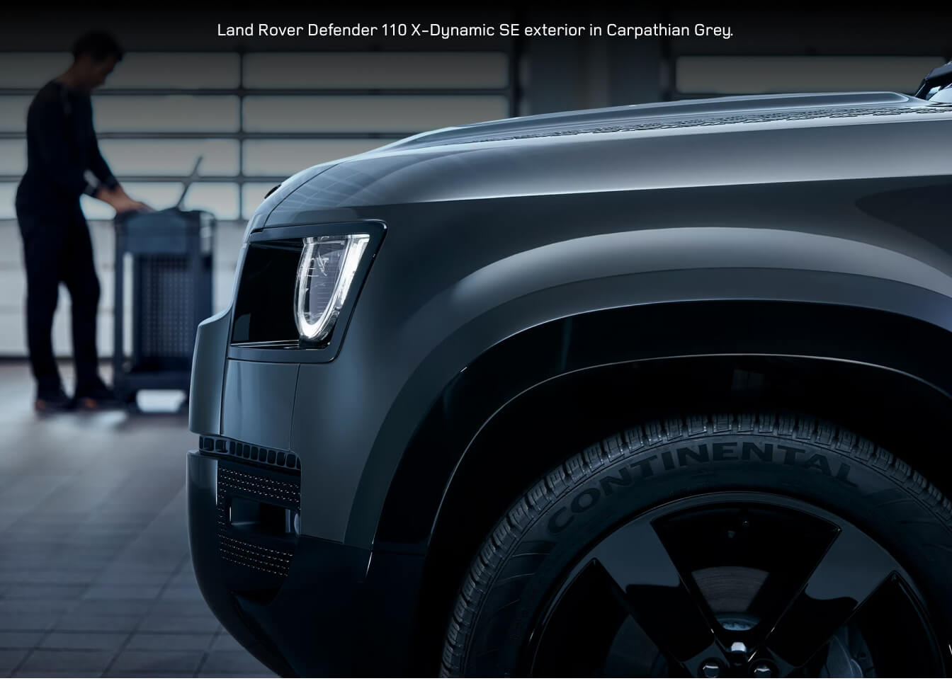 Front three-quarter close-up of a 2026 Land Rover Defender 110 X-Dynamic SE in Carpathian Grey undergoing service diagnostics.