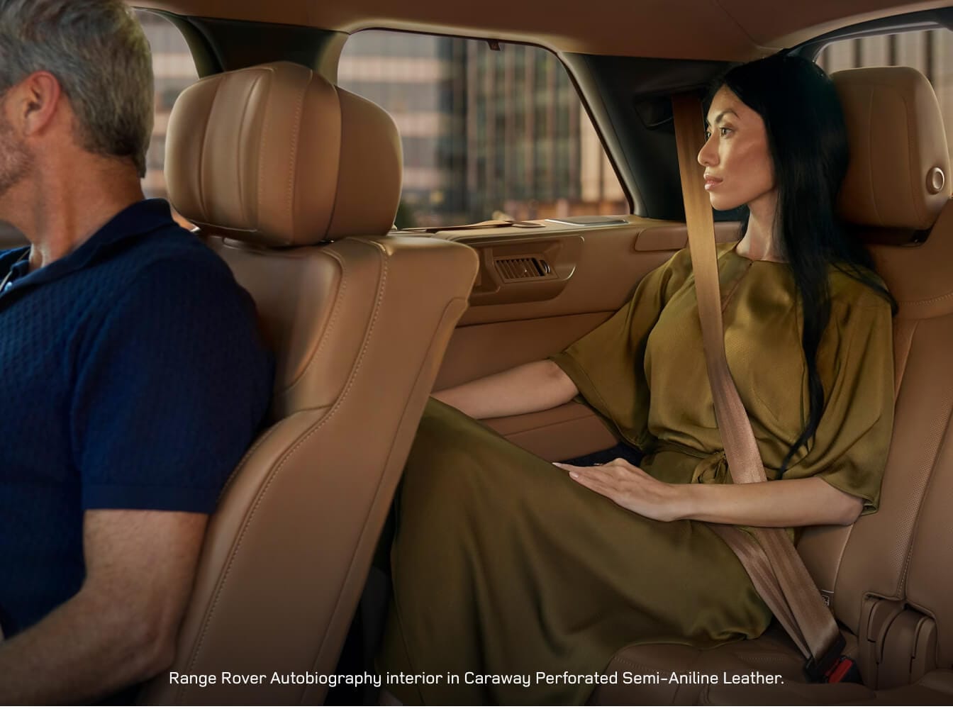 Rear passenger view of a Land Rover Range Rover Autobiography with a woman on premium Caraway leather seats.