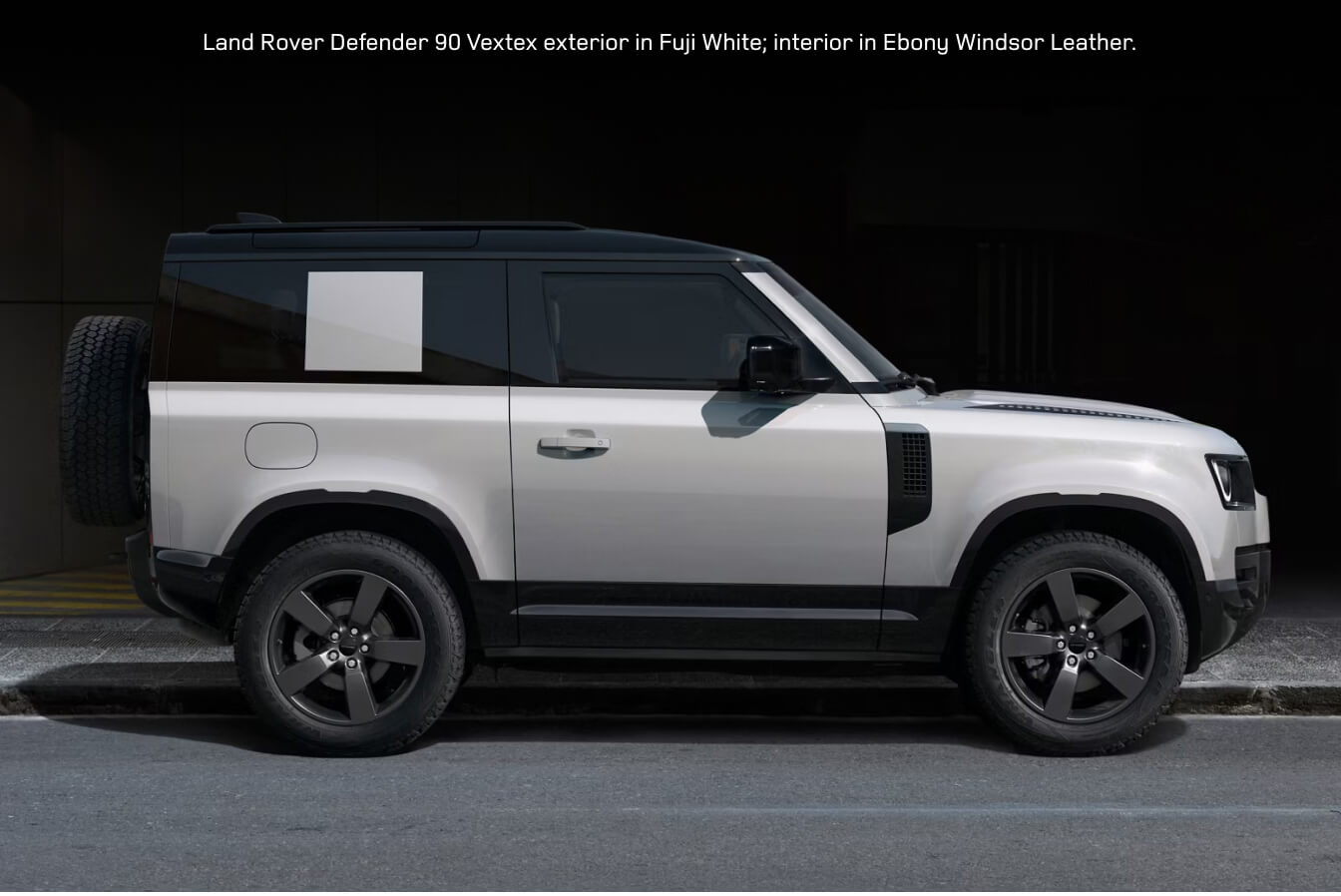 Side profile view of a 2026 Land Rover Defender 90 Vertex in Fuji White parked along an urban street.