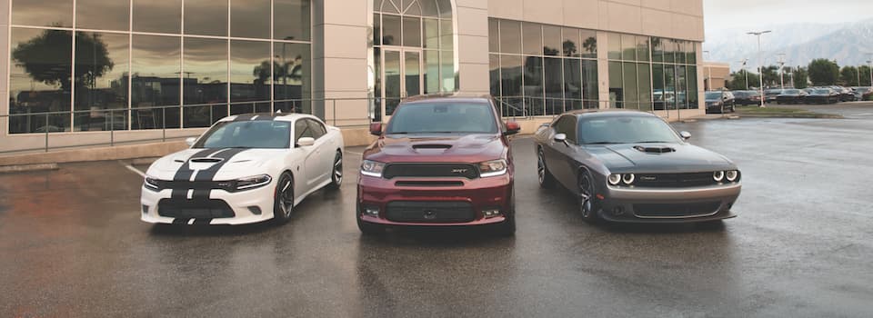 A Dodge Charger, Durango and Challenger parked in front of a dealership