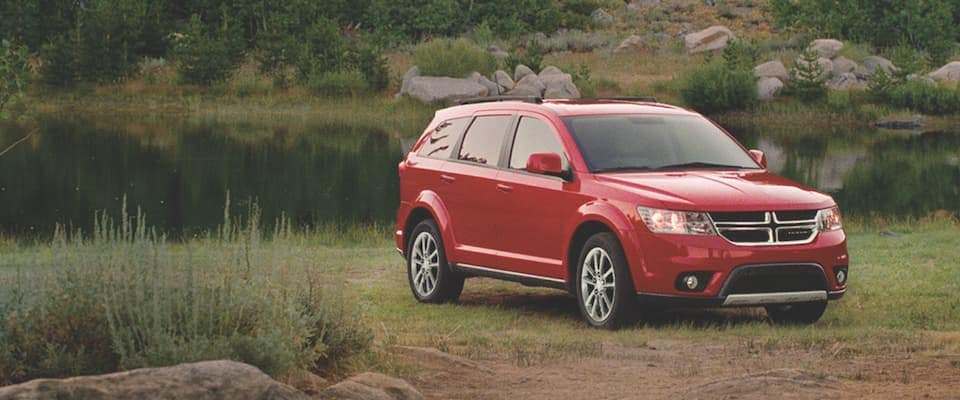 Red Dodge Journey parked by a lake