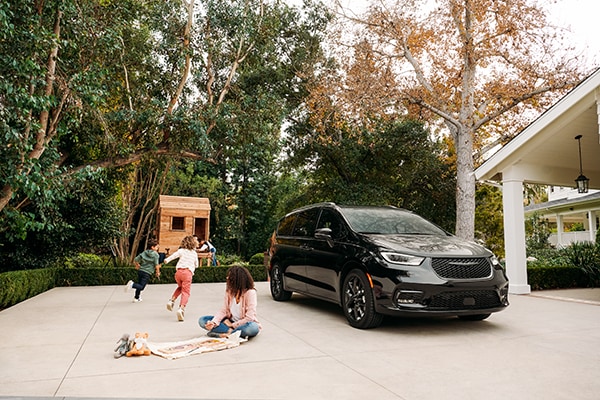 Kids playing in a driveway with a Pacifica parked nearby